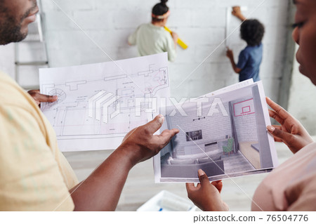 Hands of African couple looking through and discussing papers with draft and interior of living-room 76504776