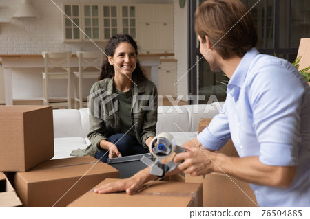 Close up happy family preparing to relocation, packing cardboard boxes 76504885