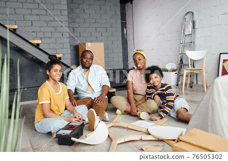Happy young African family of father, mother and kids assembling wooden chair together 76505302