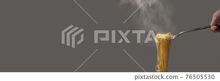 Banner with traditional Italian hot spaghetti hanging from the fork hold by hand with vapor around at solid background with copy space for text. 76505530