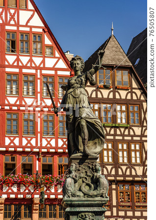 Statue a judge woman with scales and sword with old traditional wooden made houses in downtown of Frankfurt, Germany, details, closeup 76505807