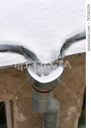 Snow and frozen water blocked the drain on the roof of the old house 76506204