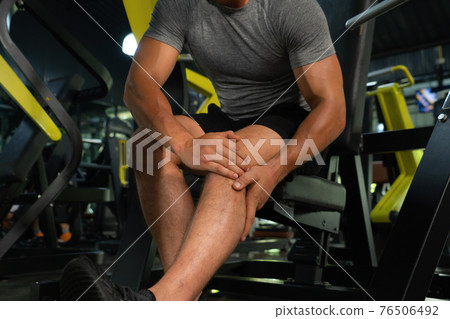 A man injuredand painful from an accident. Leg pain. Muscle strength training workout at gym fitness center club. Exercise indoor with sport equipment. Athletic. People lifestyle. Hurt or cramps. A man injuredand painful from an accident. Leg pain. Muscle strength training workout at gym fitness center club. Exercise indoor with sport equipment. Athletic. People lifestyle. Hurt or cramps. 76506492