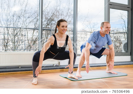 Smiling people exercise yoga with wide legs Smiling people exercise yoga with wide legs 76506496