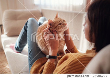 Young woman resting with pet in sofa at home. 76506727