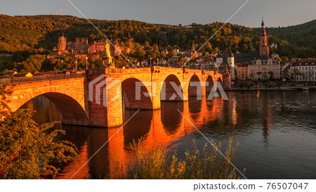 Panoramic view during red sunset at old bridge, downtown and castle in Heidelberg, Germany Panoramic view during red sunset at old bridge, downtown and castle in Heidelberg, Germany 76507047