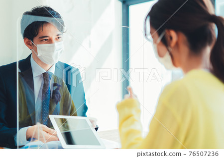 A man in a mask serving customers through an acrylic board A man in a mask serving customers through an acrylic board 76507236