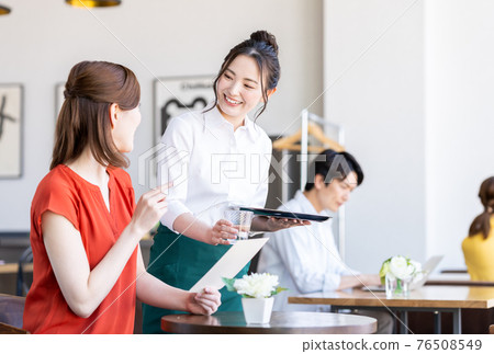 Staff serving young women ordering at the cafe Staff serving young women ordering at the cafe 76508549