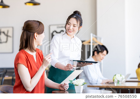Staff serving young women ordering at the cafe Staff serving young women ordering at the cafe 76508550