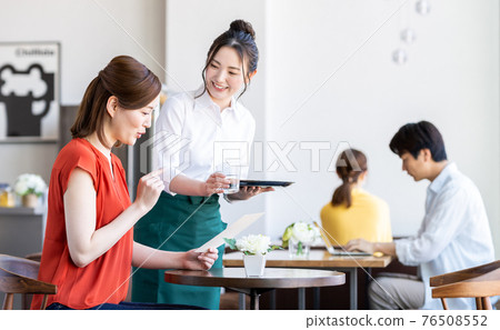 Staff serving young women ordering at the cafe Staff serving young women ordering at the cafe 76508552