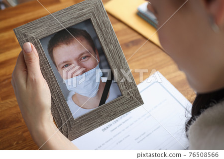 Woman crying over portrait of deceased young man closeup 76508566