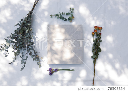 一本放在白色織物上的書,有自然光和植物的陰影 一本放在白色織物上的書,有自然光和植物的陰影 76508834