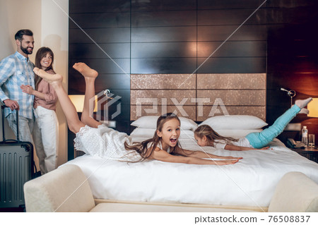Two girls having fun in the room, parents watching them 76508837