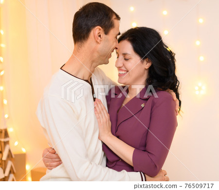 portrait of adult couple in home interior decorated with lights 76509717