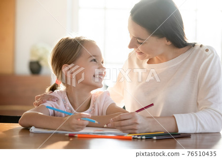 Smiling young mom and little daughter drawing Smiling young mom and little daughter drawing 76510435