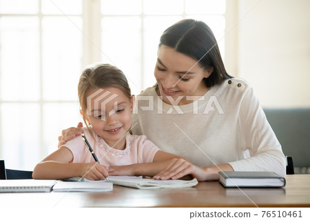 Happy young mom and little daughter do homework Happy young mom and little daughter do homework 76510461
