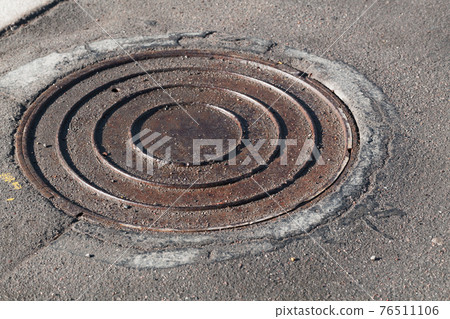 Round sewer manhole hatch is in asphalt road 76511106