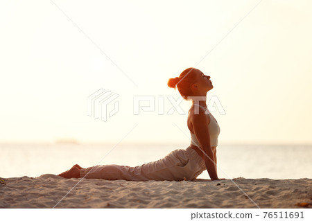 Woman practicing yoga on sandy beach Woman practicing yoga on sandy beach 76511691