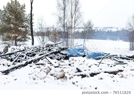 Ruins of house burned in fire conflagration on smoke snow winter landscape background 76511820