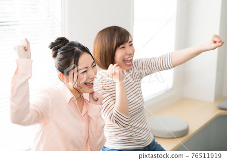Two women watching sports online on TV 76511919