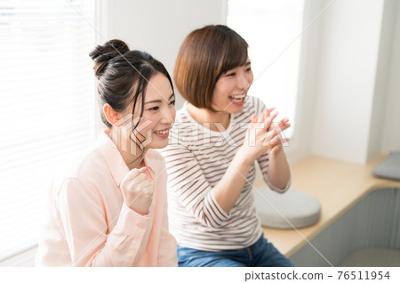 Two women watching sports online on TV 76511954