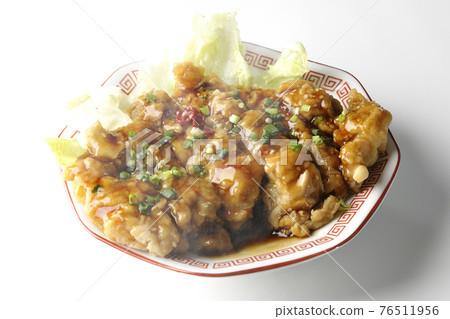 在白色背景的八角形盤子上拍攝了一隻熱油沙丁魚雞，上面放著大量醬汁和蔥 76511956