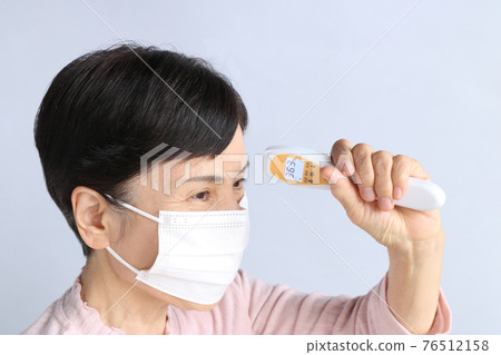 側身戴著口罩並使用非接觸式溫度計 36.3 度的老年婦女 側身戴著口罩並使用非接觸式溫度計 36.3 度的老年婦女 76512158