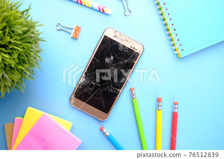 Top view of broken smart phone and stationary on color background Top view of broken smart phone and stationary on color background 76512839