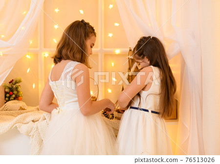portrait of a child girls in home interior decorated with holiday lights and gifts portrait of a child girls in home interior decorated with holiday lights and gifts 76513026