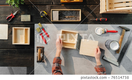 Top view of unrecognizable woman making wooden boxes, small business and desktop concept. Top view of unrecognizable woman making wooden boxes, small business and desktop concept. 76514738