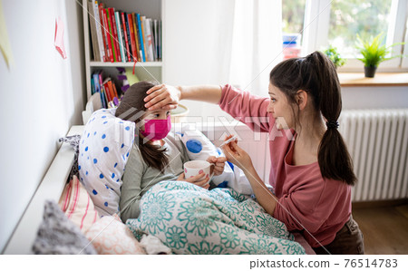 Mother looking after sick small daughter in bed at home, coronavirus concept. Mother looking after sick small daughter in bed at home, coronavirus concept. 76514783