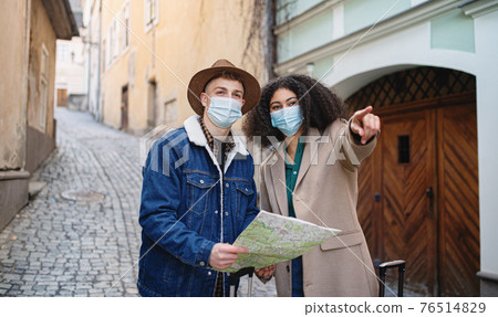 Young couple tourists with map on holiday in old town, coronavirus concept. Young couple tourists with map on holiday in old town, coronavirus concept. 76514829