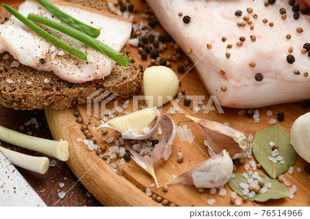 raw pork meat and lard with salt, spices and garlic on a cutting board, dark wooden background raw pork meat and lard with salt, spices and garlic on a cutting board, dark wooden background 76514966