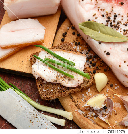 raw pork meat and lard with salt, spices and garlic on a cutting board, dark wooden background raw pork meat and lard with salt, spices and garlic on a cutting board, dark wooden background 76514979