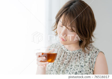 Young woman holding a cup of tea by the window Young woman holding a cup of tea by the window 76516017