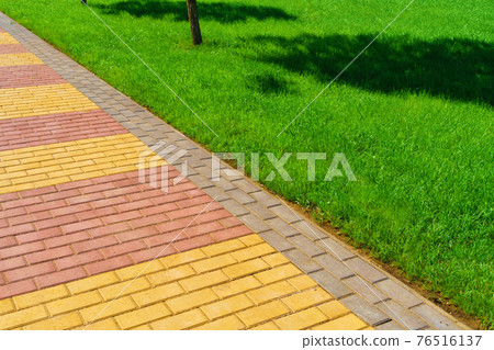 walkway made of paving slabs and green grass as a background, bright sunlight walkway made of paving slabs and green grass as a background, bright sunlight 76516137