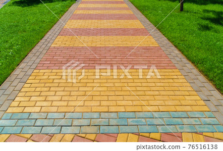walkway made of paving slabs and green grass as a background, bright sunlight walkway made of paving slabs and green grass as a background, bright sunlight 76516138