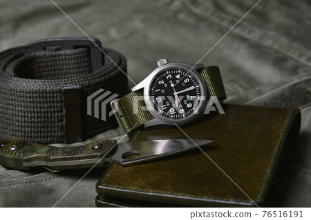 Vintage military watch with nato strap and tactical knife on green background, Classic timepiece 76516191