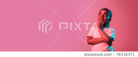 Portrait of little African-American girl isolated on pink background in neon 76516371