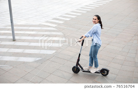 Excited lady having pleasant ride on electric kick scooter Excited lady having pleasant ride on electric kick scooter 76516704