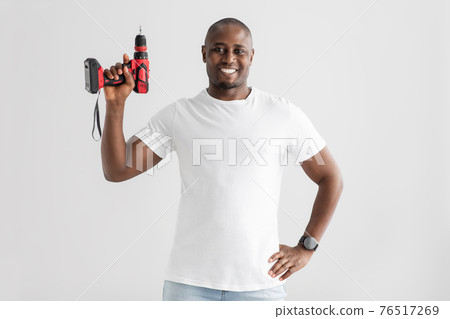 Instruments for renovation. Happy african american man holding electric drill, isolated on white background Instruments for renovation. Happy african american man holding electric drill, isolated on white background 76517269