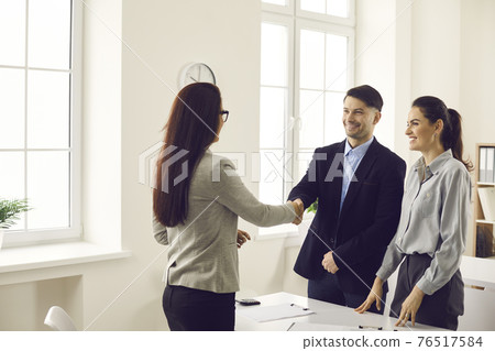 Couple and woman financial advisor sealing with handshake thanking for advice 76517584