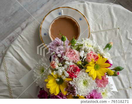 Bouquet of colorful flowers with a white cup on a white tablecloth 76518271