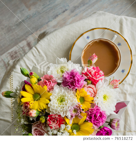 Bouquet of colorful flowers with a white cup on a white tablecloth 76518272