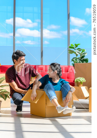 Happy young asian couple smiling relaxing and having fun while playing with cardboard box in new house, celebrating moving to new home concept Happy young asian couple smiling relaxing and having fun while playing with cardboard box in new house, celebrating moving to new home concept 76519059