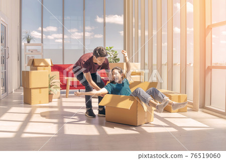 Happy young asian couple smiling relaxing and having fun while playing with cardboard box in new house, celebrating moving to new home concept Happy young asian couple smiling relaxing and having fun while playing with cardboard box in new house, celebrating moving to new home concept 76519060