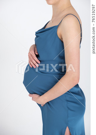 Studio portrait of young adult pregnant woman in blue dress on white gray background, happy pregnancy concept Studio portrait of young adult pregnant woman in blue dress on white gray background, happy pregnancy concept 76519297