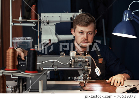 Working process of leather craftsman. Tanner or skinner sews leather on a special sewing machine, close up.worker sewing on the sewing machine 76519378