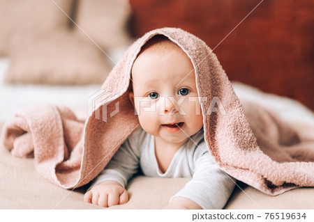 A beautiful newborn baby lying on his stomach and covered with towel. Caring for the health of children 76519634