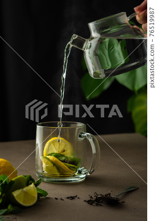 Woman pours boiling water into a mug with black tea Woman pours boiling water into a mug with black tea 76519987